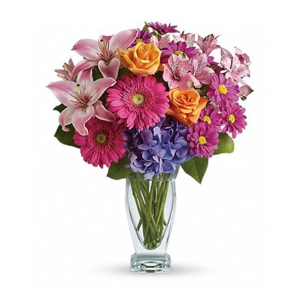Mixed bouquet of pink, purple, and orange flowers in a clear glass vase