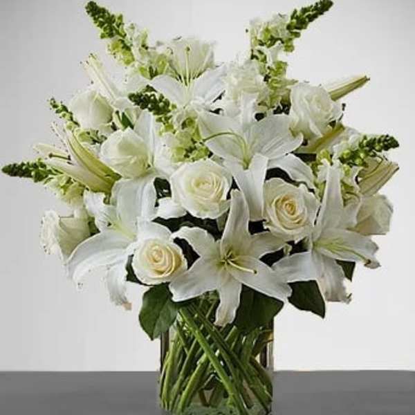 White lilies and roses arranged in a clear glass vase