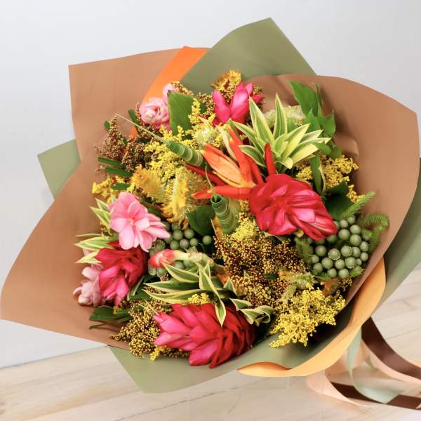 Bouquet of bright tropical flowers wrapped in brown and green paper