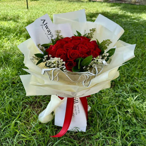 Bouquet of red roses wrapped in white paper with a red ribbon