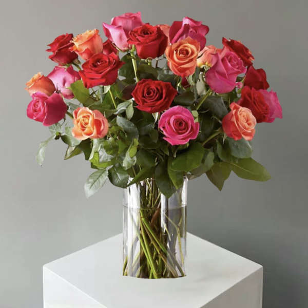 Bouquet of pink, red, and peach roses in a clear glass vase