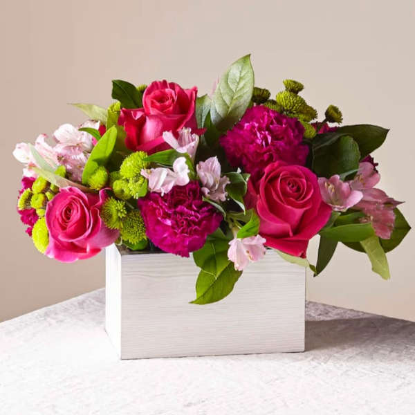 Pink roses and mixed blooms arranged in a white rectangular box