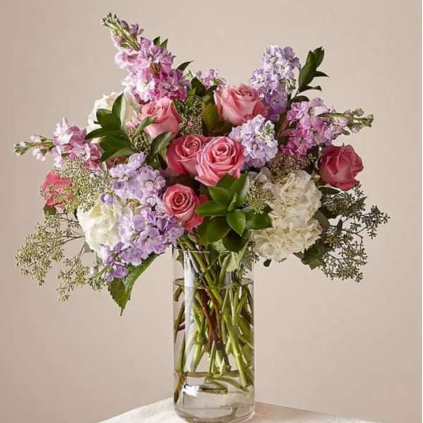 Pink and lavender flowers arranged in a clear glass vase