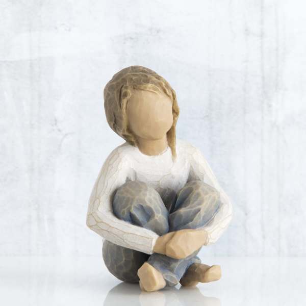 Carved figurine of a seated child with knees hugged to chest