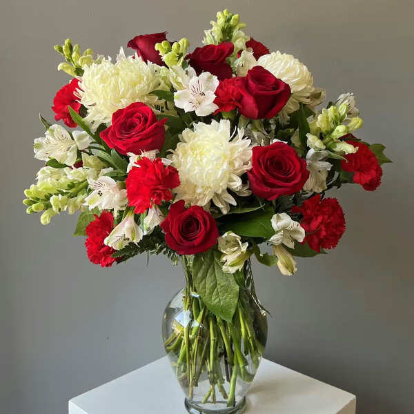 Bouquet of red roses, white chrysanthemums, and white alstroemeria in a glass vase