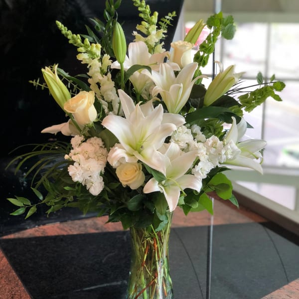 White lilies and cream roses in a clear glass vase