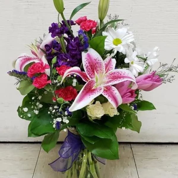 Bouquet of lilies, daisies, carnations, and purple flowers in a glass vase