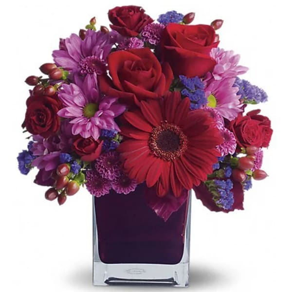 Red and purple mixed bouquet in a square glass vase