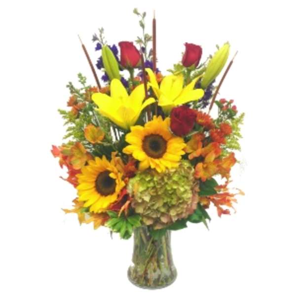 Bouquet of sunflowers, lilies, and red roses in a glass vase