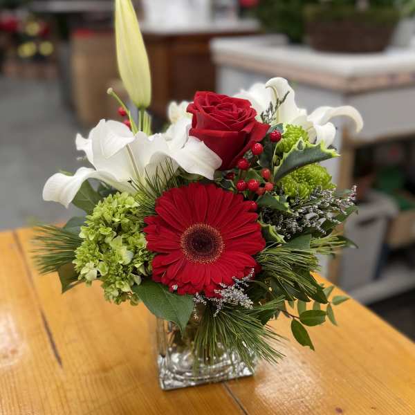 Red gerbera and rose bouquet in a clear square vase
