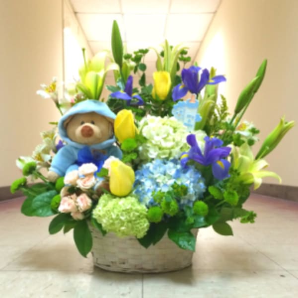 Basket arrangement with a teddy bear, lilies, tulips, and hydrangeas