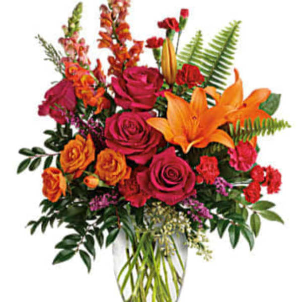 Bright mixed bouquet with roses and lilies in a glass vase