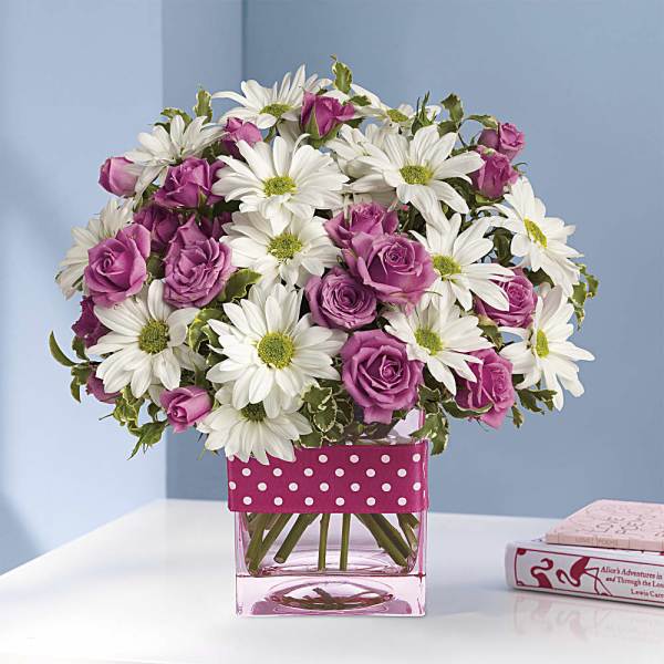Pink roses and white daisies in a pink glass vase with polka-dot ribbon