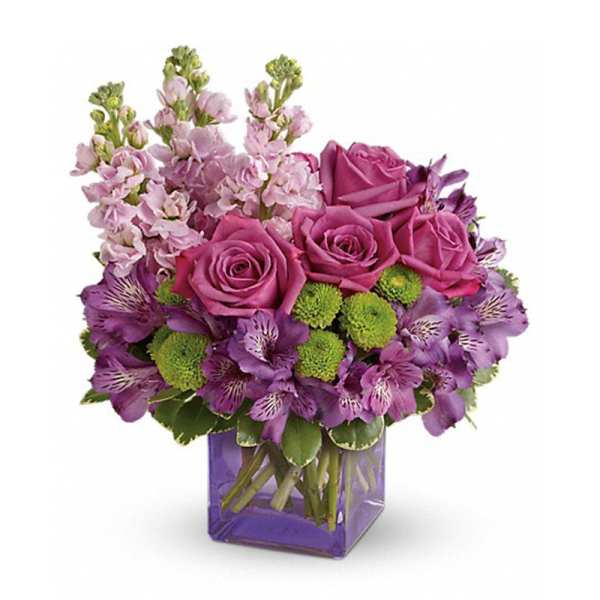Purple roses and mixed purple flowers in a square glass vase