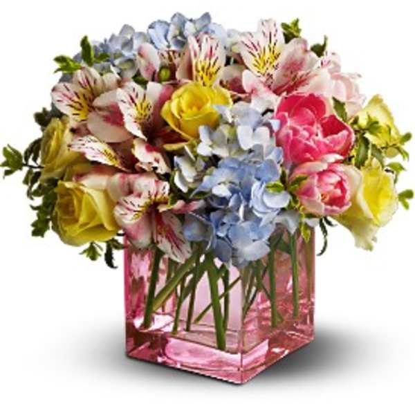 Mixed bouquet of roses, alstroemeria, and hydrangeas in a pink glass vase