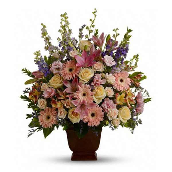 Tall pastel arrangement of pink lilies, gerberas, and cream roses in a brown pedestal vase