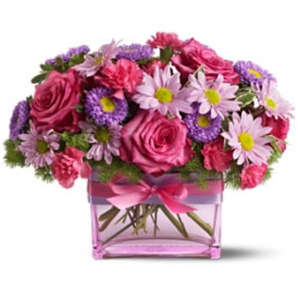 Pink roses and purple daisies in a pink glass vase with a ribbon