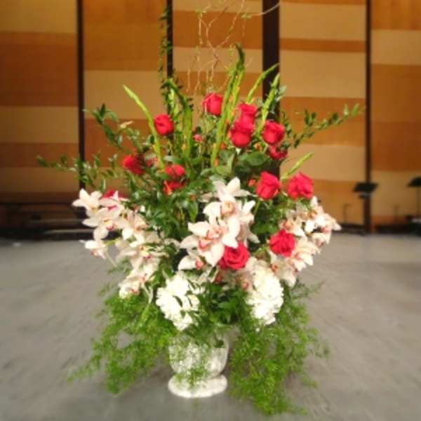 Tall arrangement of red roses and white lilies in a white urn-style vase