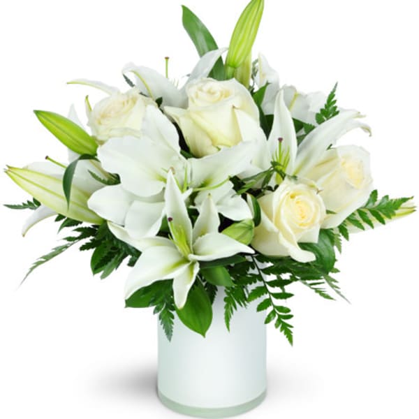 White lilies and roses arranged in a glass vase