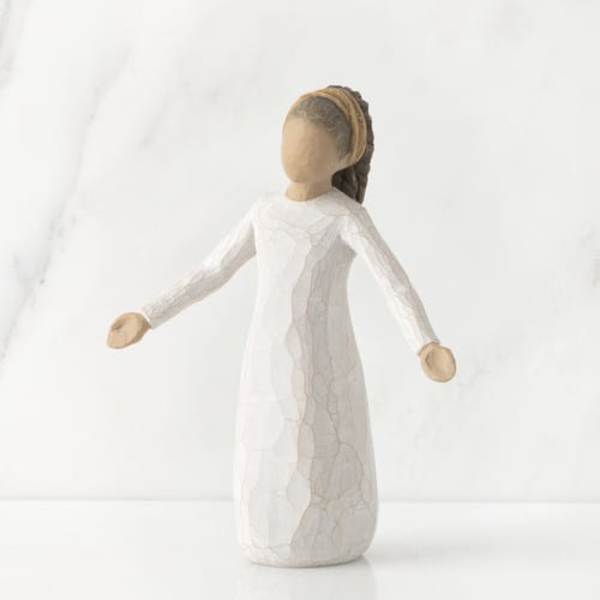 Small faceless figurine in a white dress with outstretched arms