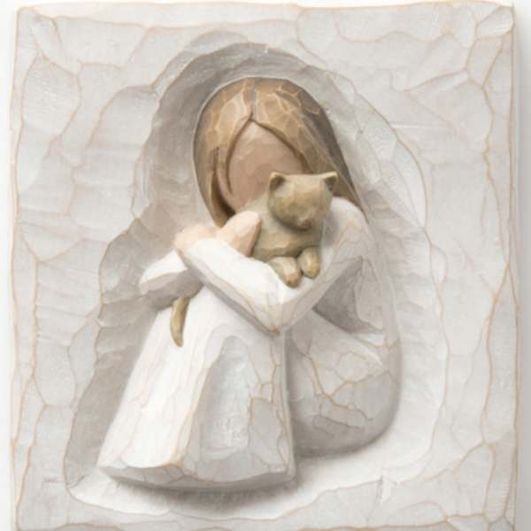 Carved figurine of a girl holding a teddy bear