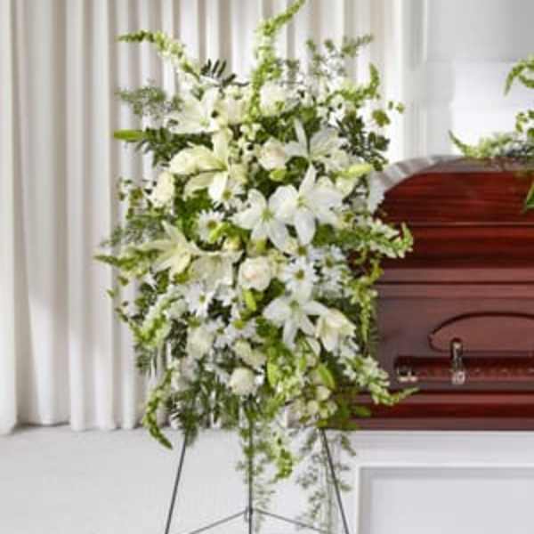 Tall white floral spray beside a wooden casket