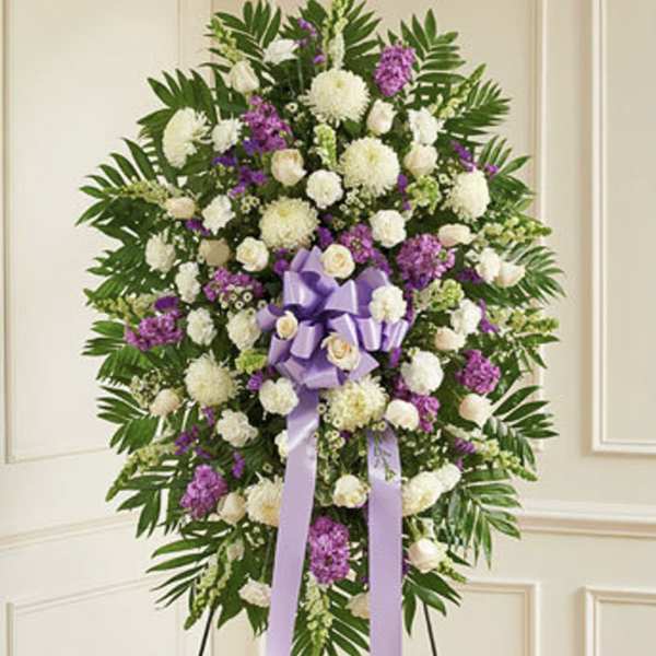 Standing floral spray with white and purple flowers and a lavender ribbon