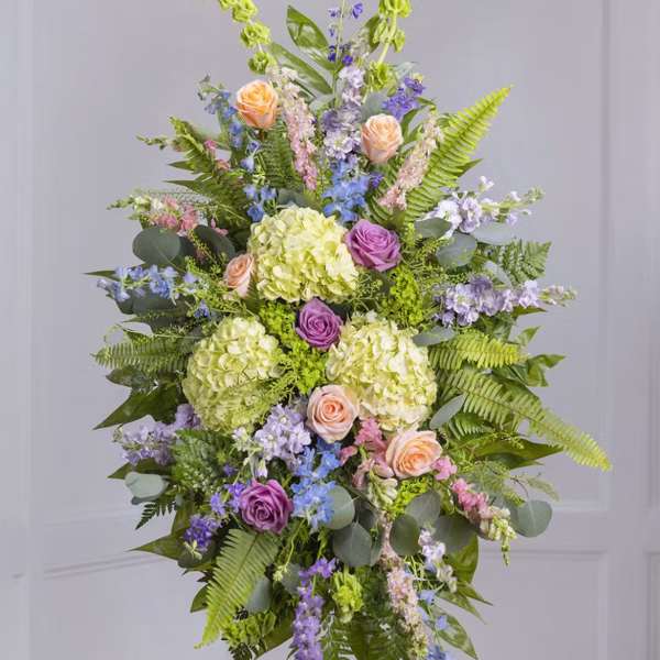 Tall floral standing spray with pastel roses, hydrangeas, and purple blooms