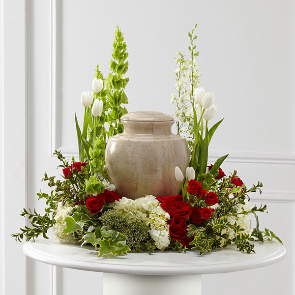 Red roses and white tulips arranged around a beige urn