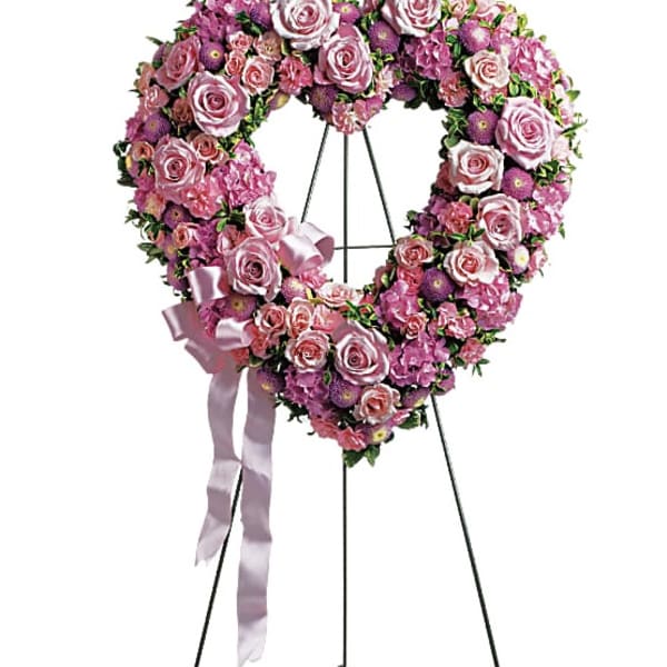 Heart-shaped pink rose wreath on a stand with a satin ribbon