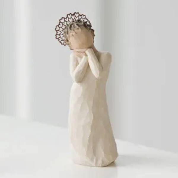 Small angel figurine in a cream dress with hands at its face
