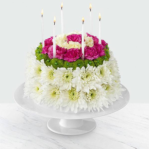 Round floral cake with white and pink flowers and tall candles