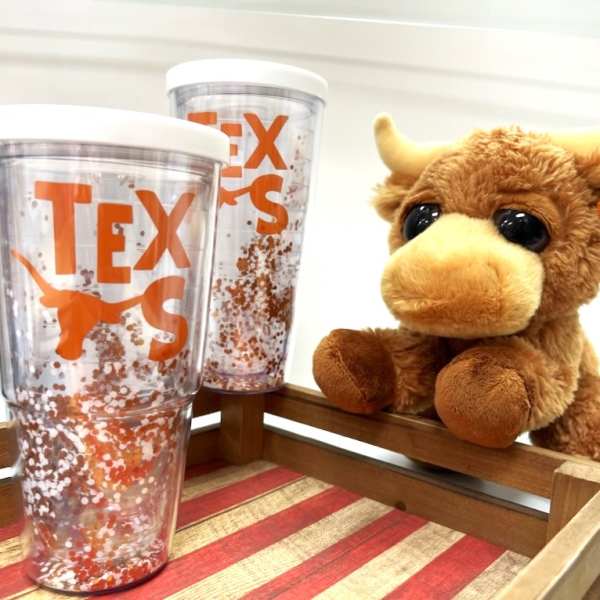 Set with two orange TEXAS glitter tumblers and a plush longhorn toy on a wooden tray.