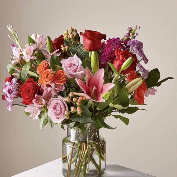 Mixed bouquet of roses, lilies, and alstroemeria in a glass vase