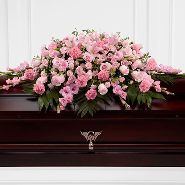 Pink floral spray arranged on a dark casket