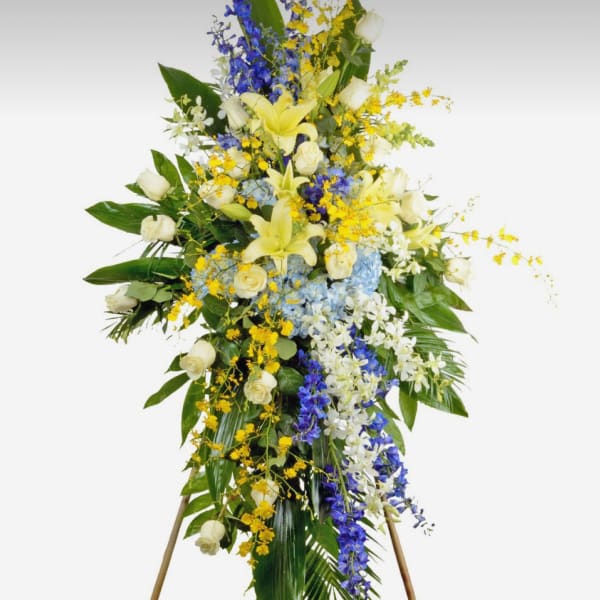 Tall standing floral spray with white roses, lilies, and blue and yellow flowers