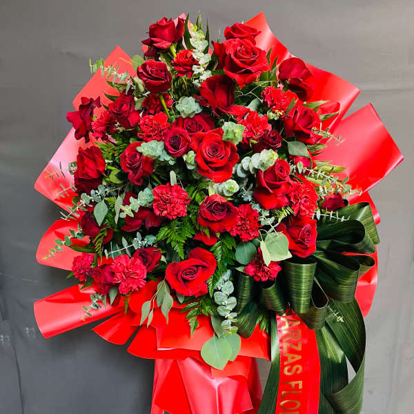 Large bouquet of red roses and carnations with red wrapping and ribbon