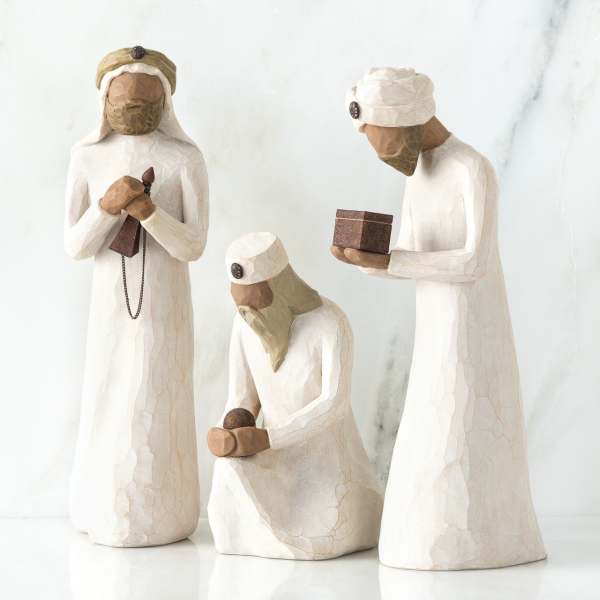 Three carved nativity figurines in white robes holding gifts