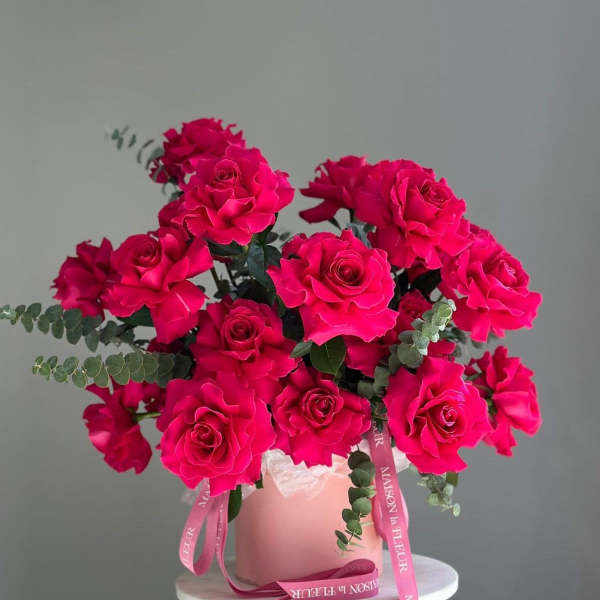 Hot pink roses arranged in a blush vase with pink ribbons