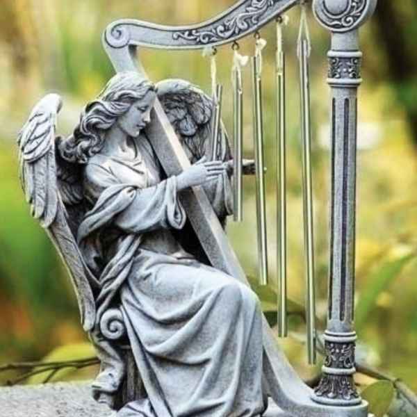 Stone angel statue playing a harp outdoors
