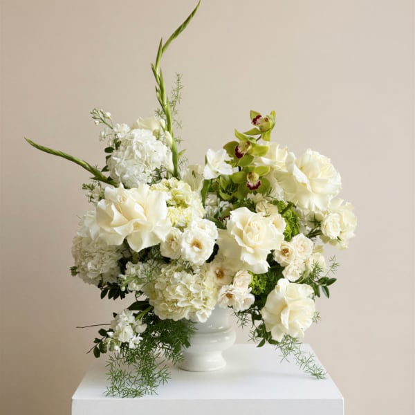 White floral arrangement in a white vase with tall green stems