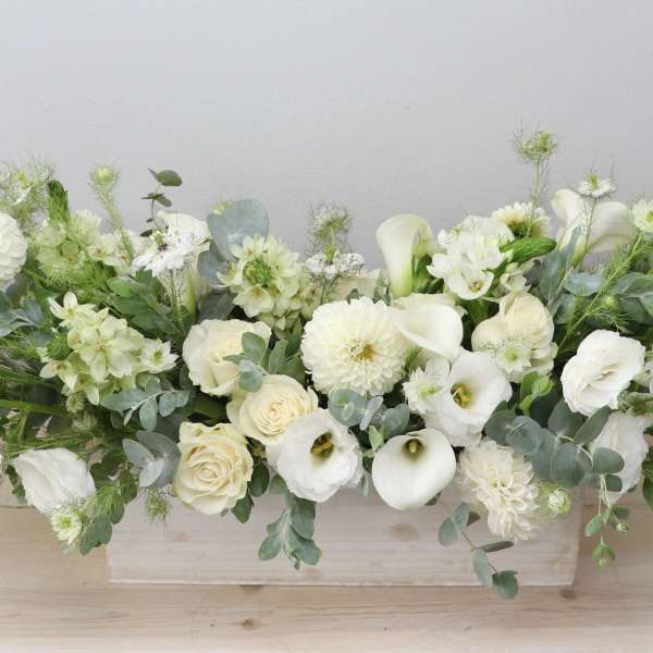Long white floral arrangement in a low rectangular container