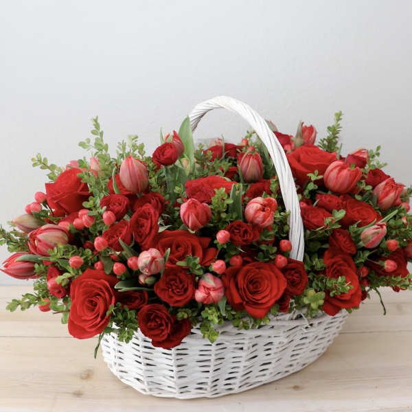 Basket of red roses and pink tulips with greenery