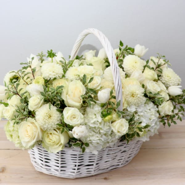 White flower basket with roses, tulips, and mums in a wicker basket