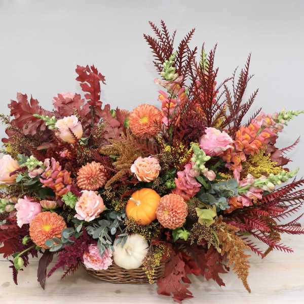 Autumn floral arrangement in a wicker basket with orange and pink blooms