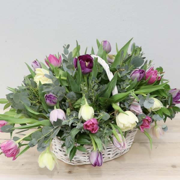 Basket of pink, purple, and white tulips with greenery