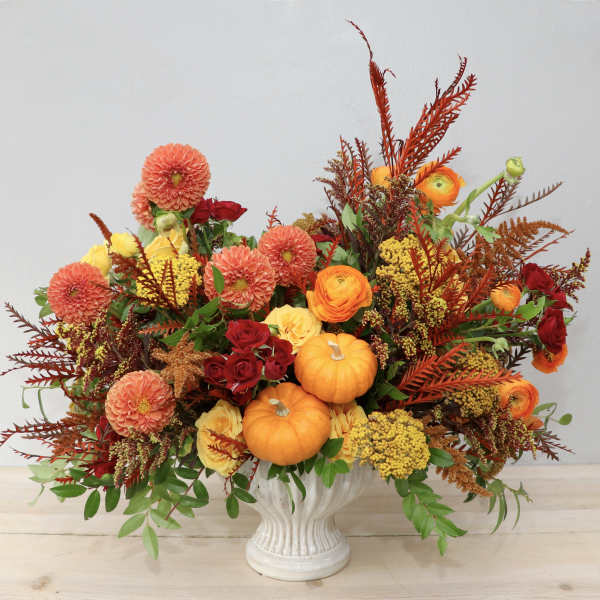 Autumn floral arrangement with pumpkins in a white vase