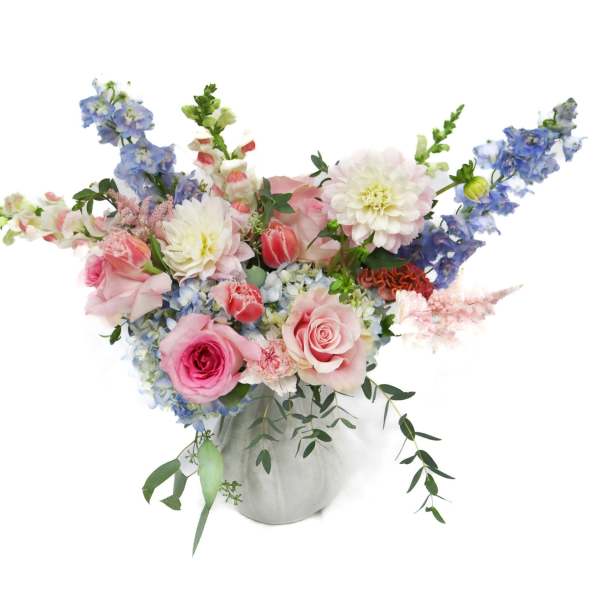 Pink and blue mixed flower arrangement in a white vase