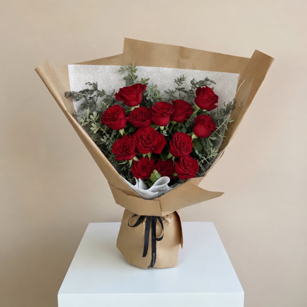 Bouquet of red roses wrapped in brown paper with a black ribbon