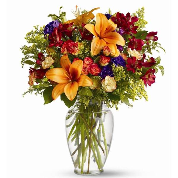 Mixed bouquet of lilies, roses, and alstroemeria in a clear glass vase